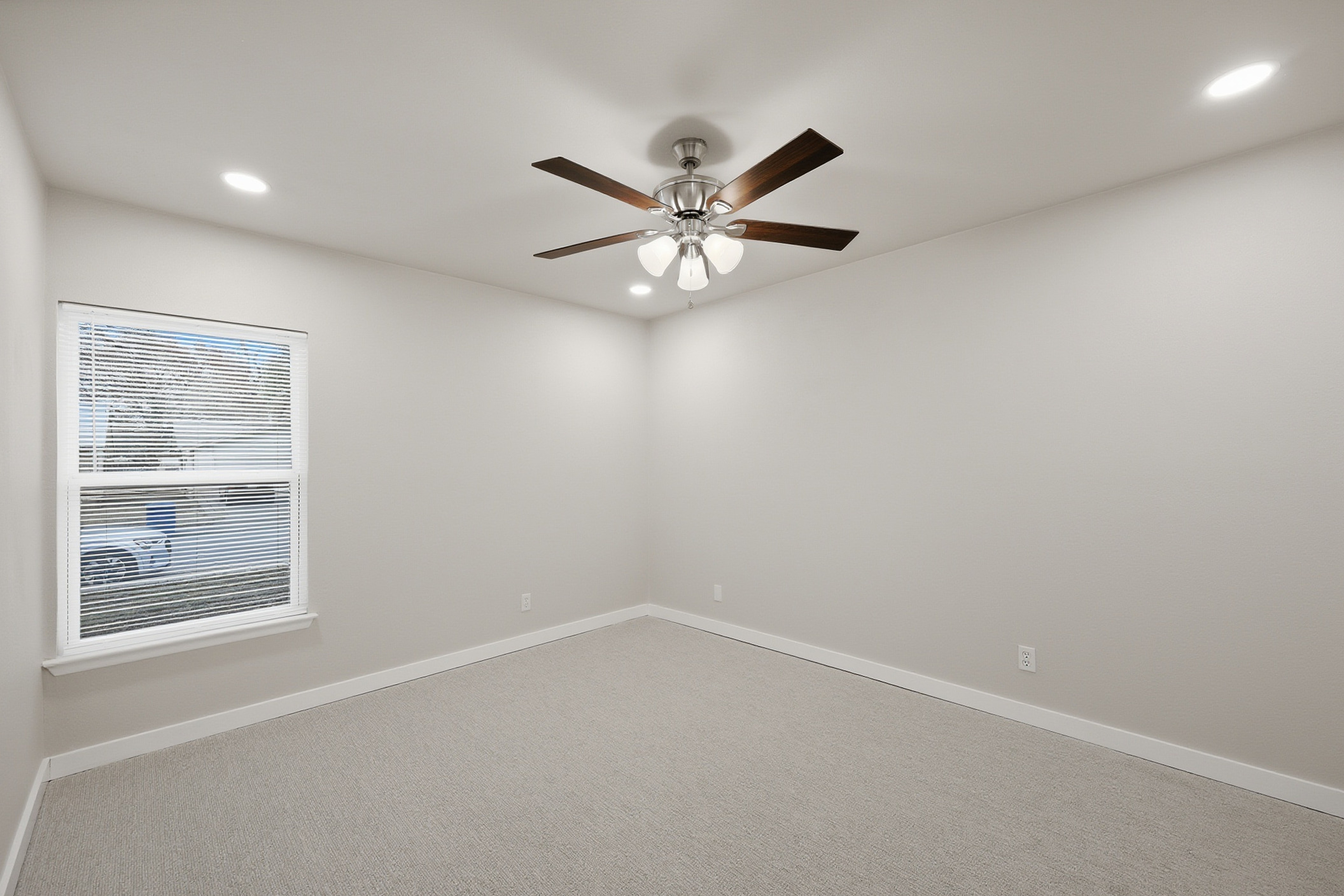 Bedroom with ceiling fan, side window, and neutral carpet flooring